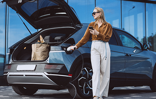 Voiture avec coffre ouvert et femme la rechargeant